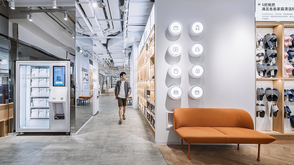 A person walking in a room with a wall of clocks.